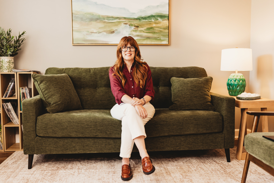 Lisa Giebelhaus sits on a green sofa in a bright consulting room, smiling at the camera.