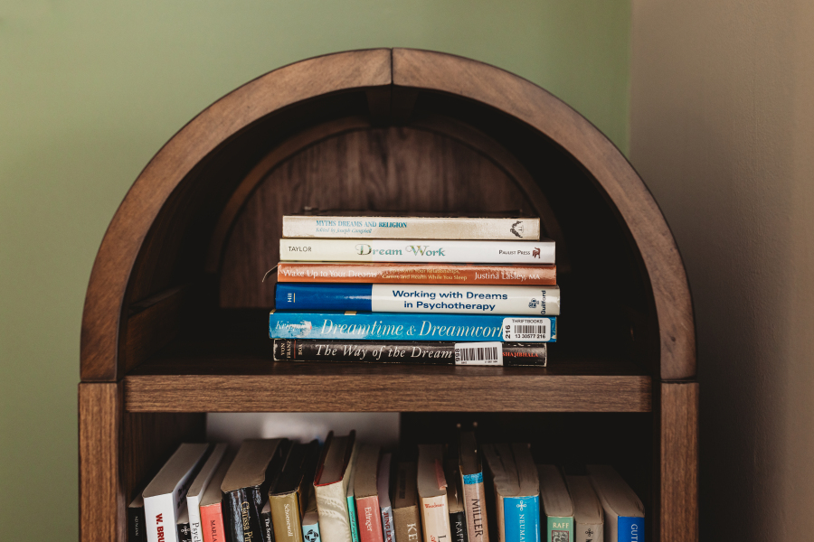 A stack of books about dreams and dream work resting on the arched wooden bookshelf in Lisa Giebelhaus's office.
