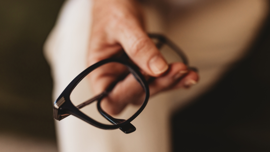 Lisa Giebelhaus holding her dark-framed reading glasses in one hand