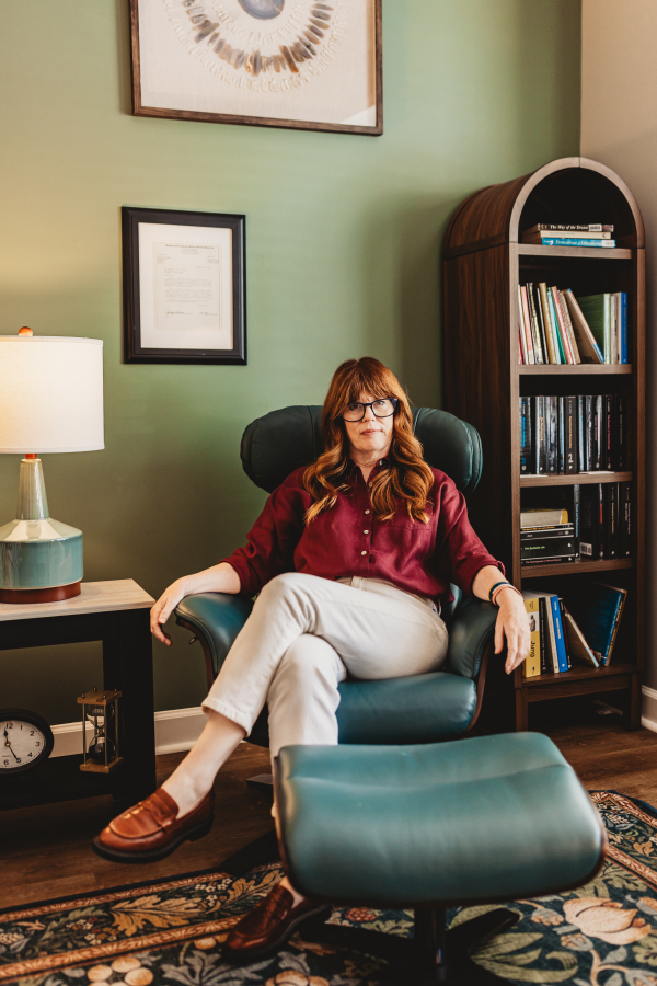 Lisa Giebelhaus sits back in the green leather chair in her counseling office, looking at the camera.